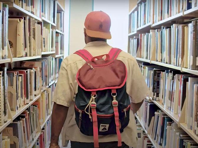 西雅图州立大学校友奥姆尼·洛特在艾姆斯图书馆里走过一排书